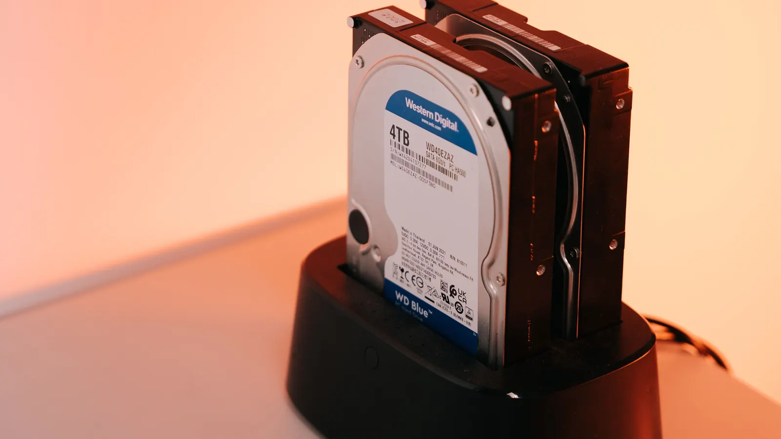 External hard drives on a docking station under warm orange lighting